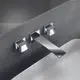Waschtischarmatur in Chrome von Ideal Standard mit eckigen Rosetten und einem langen Auslauf, montiert an einer Wand über einem Waschbecken.